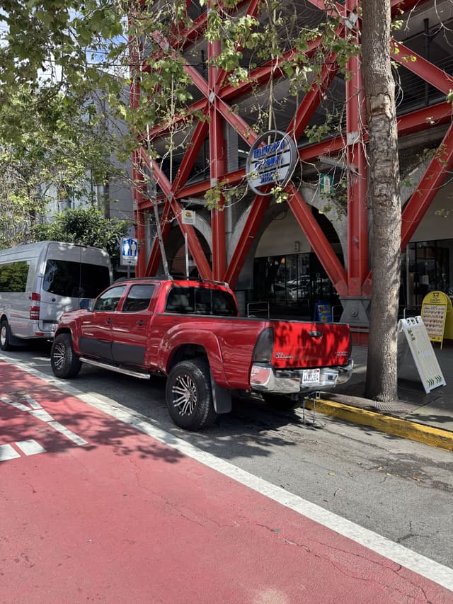 a photo of a red car between a red bus lane and red building